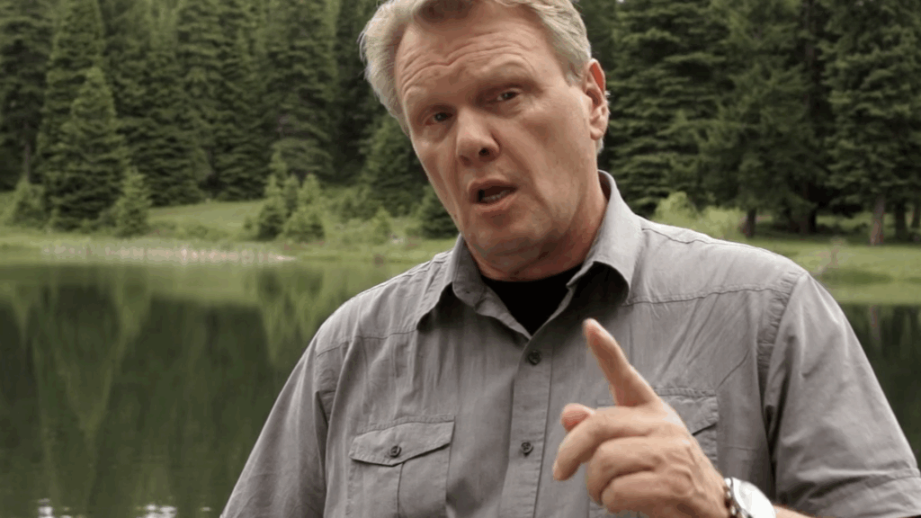 "Rock Thomson, a rugged filmmaker in his mid-50s, performs one of his iconic standups, holding a camera and gesturing toward massive footprints by the edge of Spirit Lake, with the breathtaking wilderness as his backdrop." The Ultimate Cult Bigfoot Adventure Movie