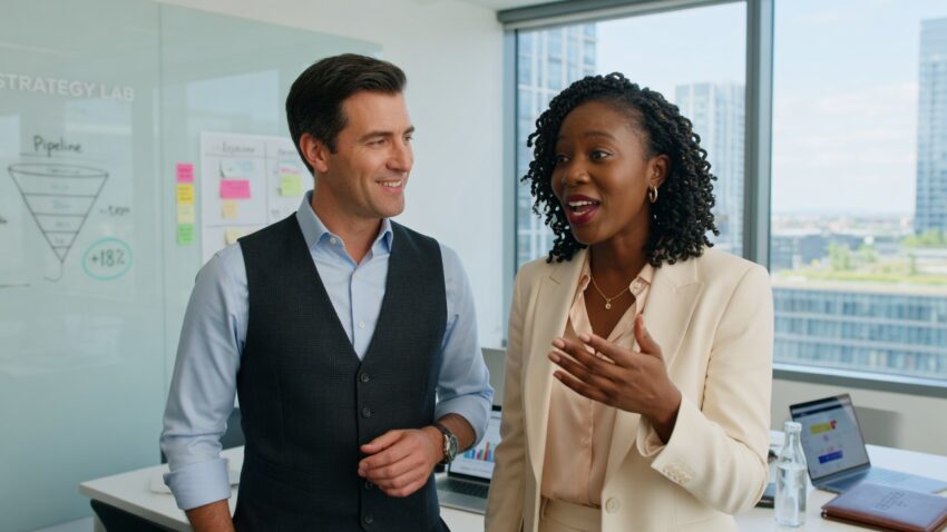 Confident, professional salespeople in their mid-30s, sharp and approachable, standing in a bright, discussing their great career in sales. Discussing their better future.